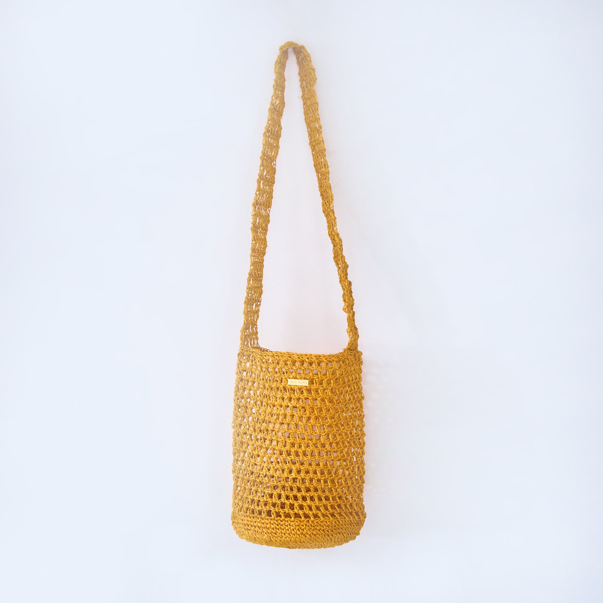 Aura Solar Ember yellow crossbody woven bag handcrafted from natural fique fiber, designed by Oda Nova to honor feminine strength and Colombian craftsmanship.