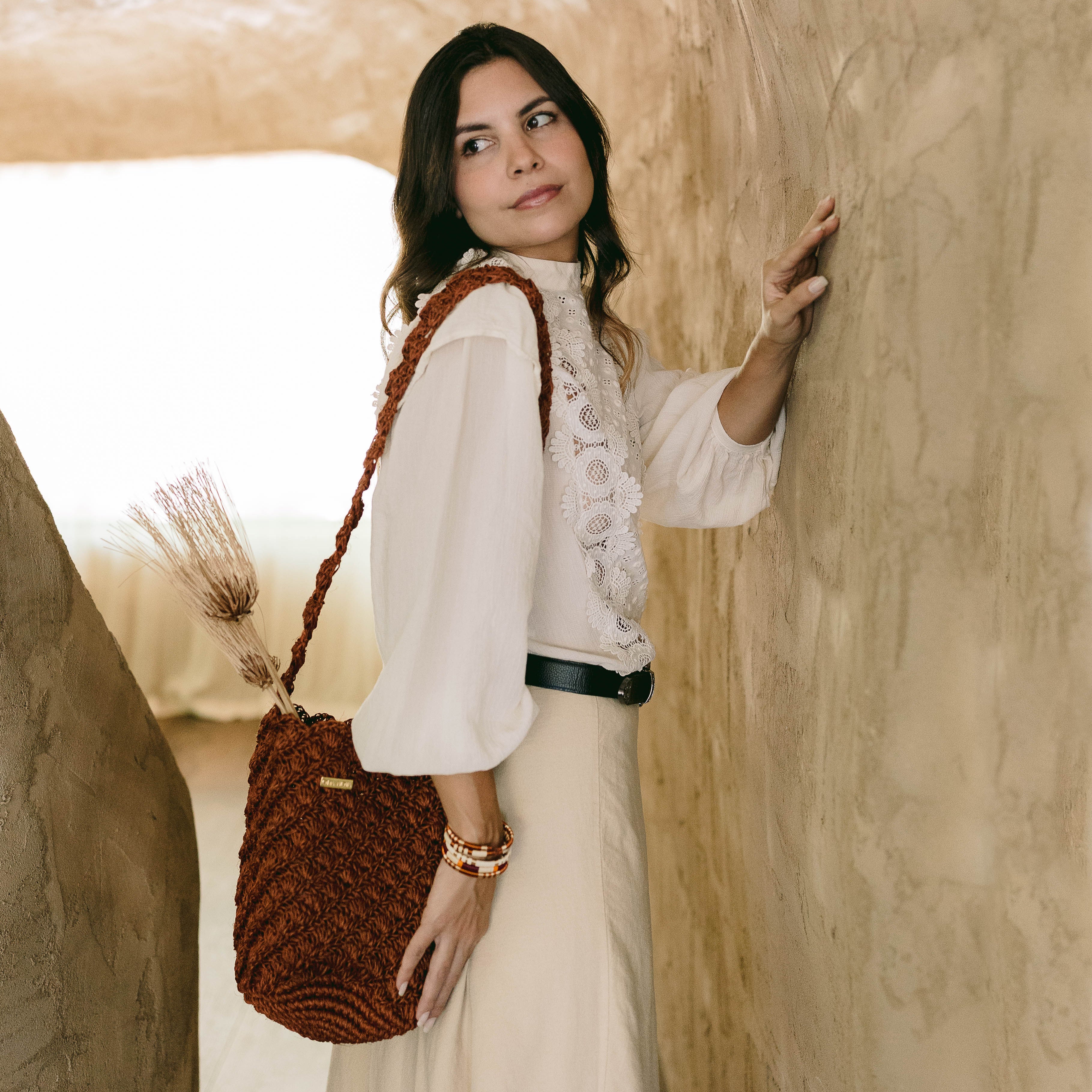 Woman holding a handmade oda nova woven bag in a rustic setting