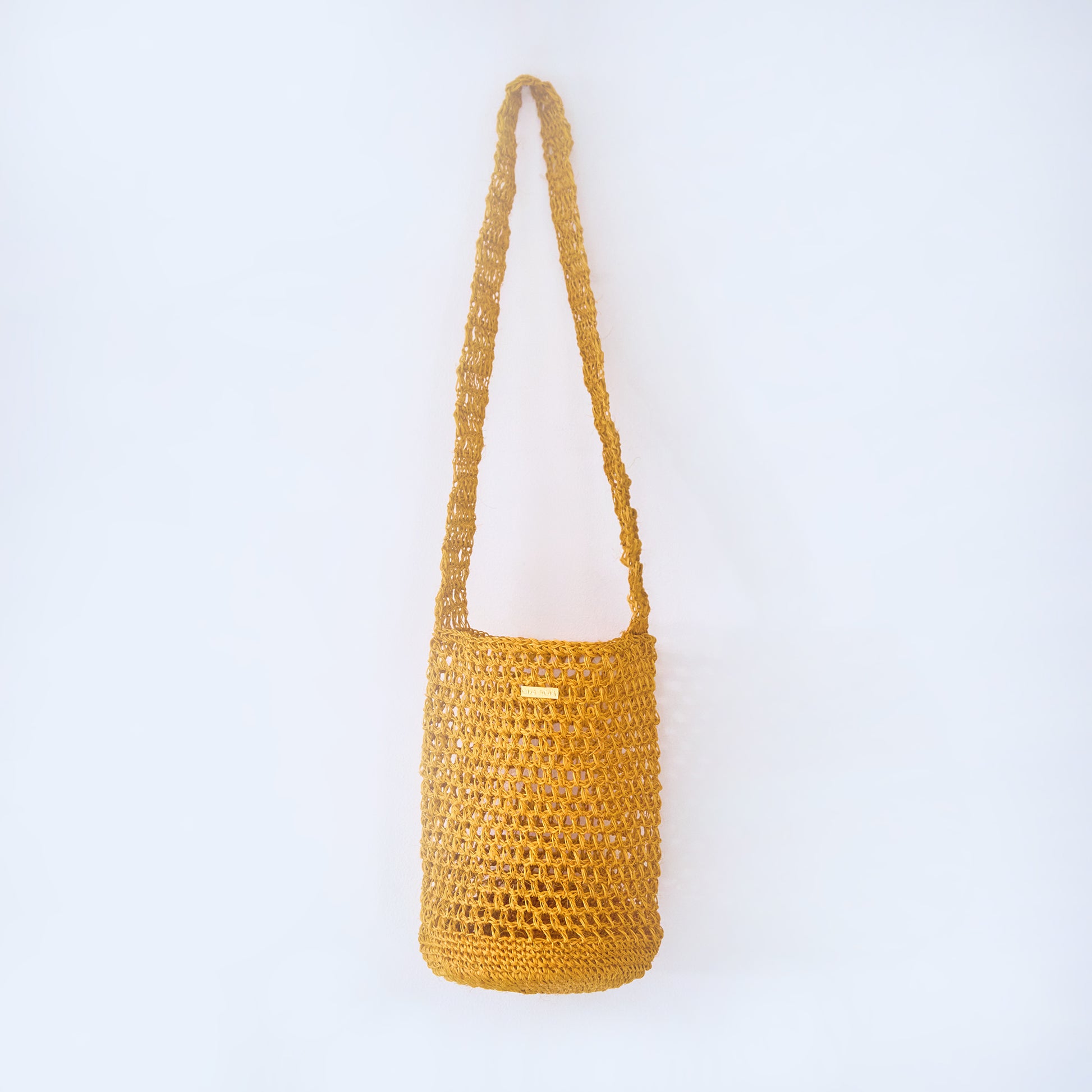 Aura Solar Ember yellow crossbody woven bag handcrafted from natural fique fiber, designed by Oda Nova to honor feminine strength and Colombian craftsmanship. 