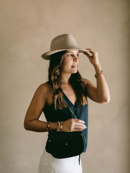 Woman wearing a beige hat and black top against a beige background
