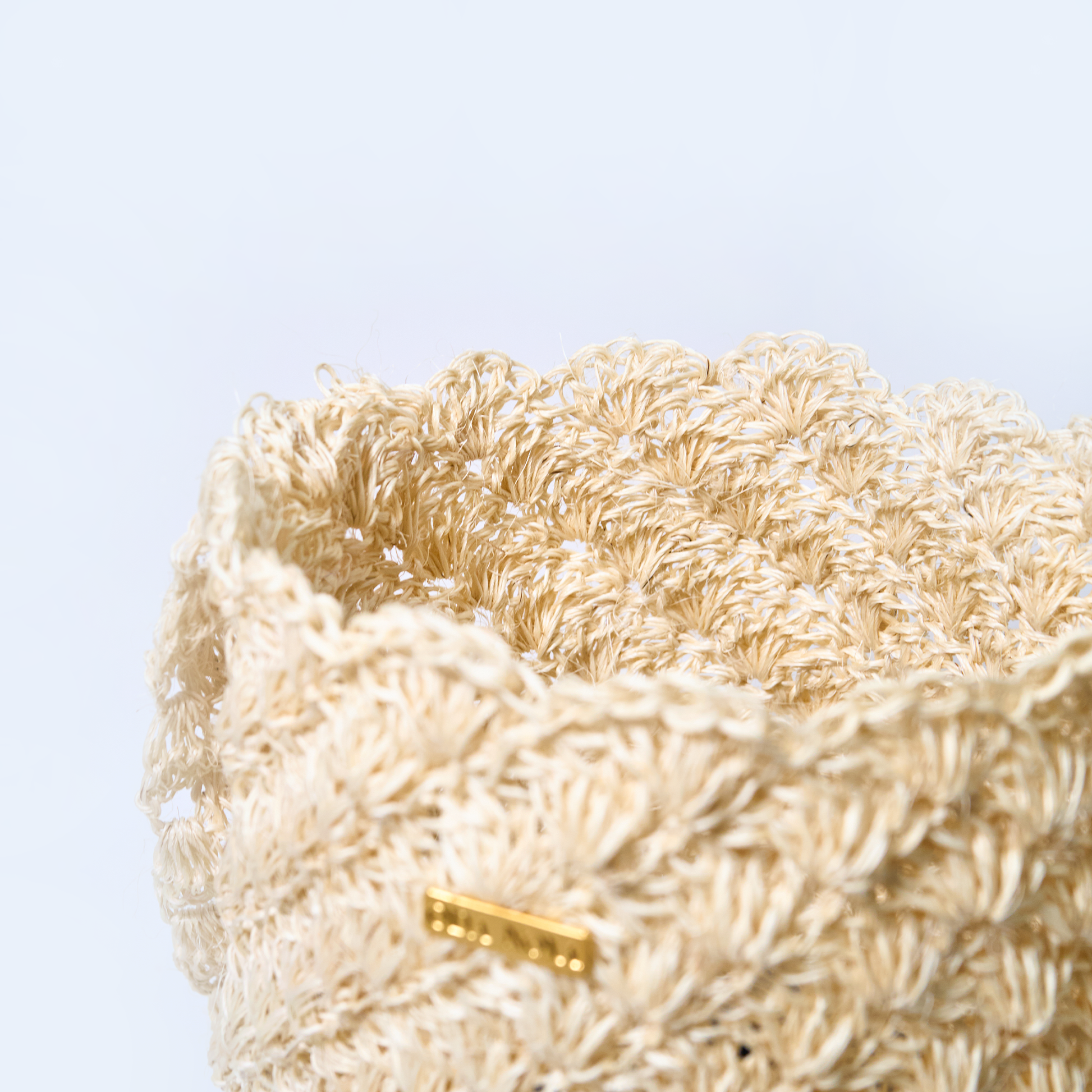 Close-up  solstice handcrafted crossbody bag made from natural fique fiber in beige, designed by Oda Nova with ancestral Colombian techniques

Closeup with a gold tag on a light blue background