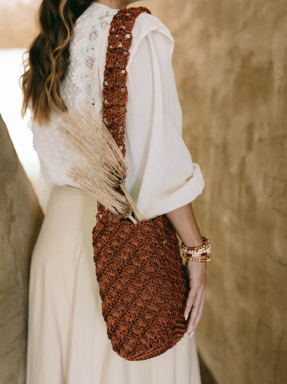 Person holding a brown handmade oda nova woven bag with a blurred background