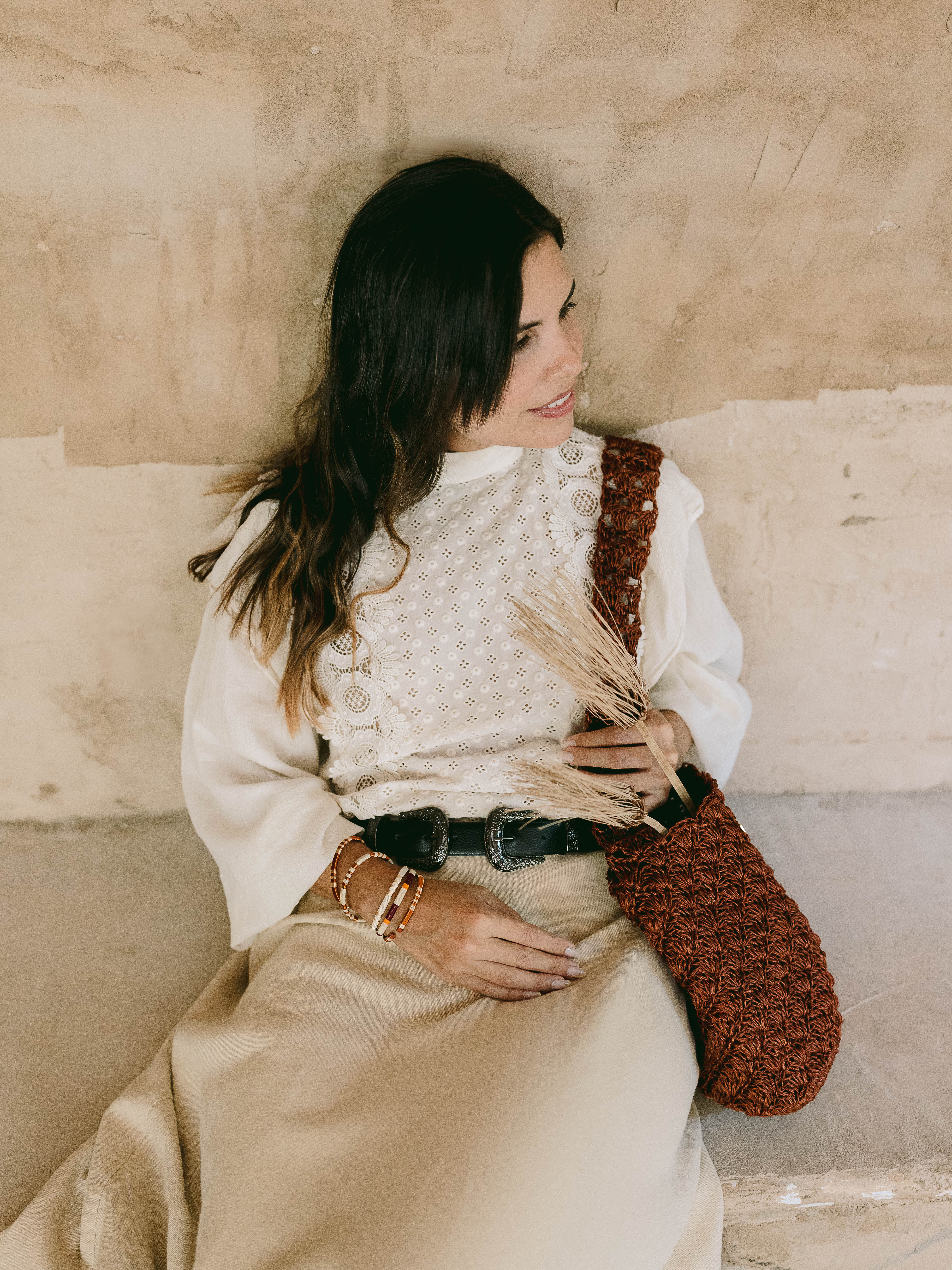 Woman holding a handmade oda nova woven bag against a beige wall